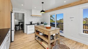 Una cucina moderna con mobili in legno, un'isola centrale e vista su una terrazza esterna.