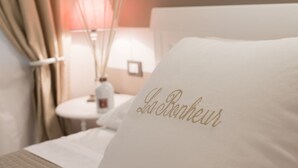 A hotel room with a bed featuring a pillow with "La Ronde" embroidered in gold. - Once in, behind the front door you will find an exclusive atmosphere, finely furnished with shabby chic details and equipped with every comfort.This is La Bonheur!At the entrance a hallway leads to 2 double rooms with beautiful en-suite bathrooms.Perfect (La Spezia)