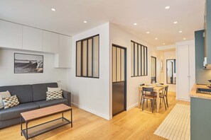 Een moderne woonkamer met een bank, salontafel en een eethoek met stoelen en een tafel.