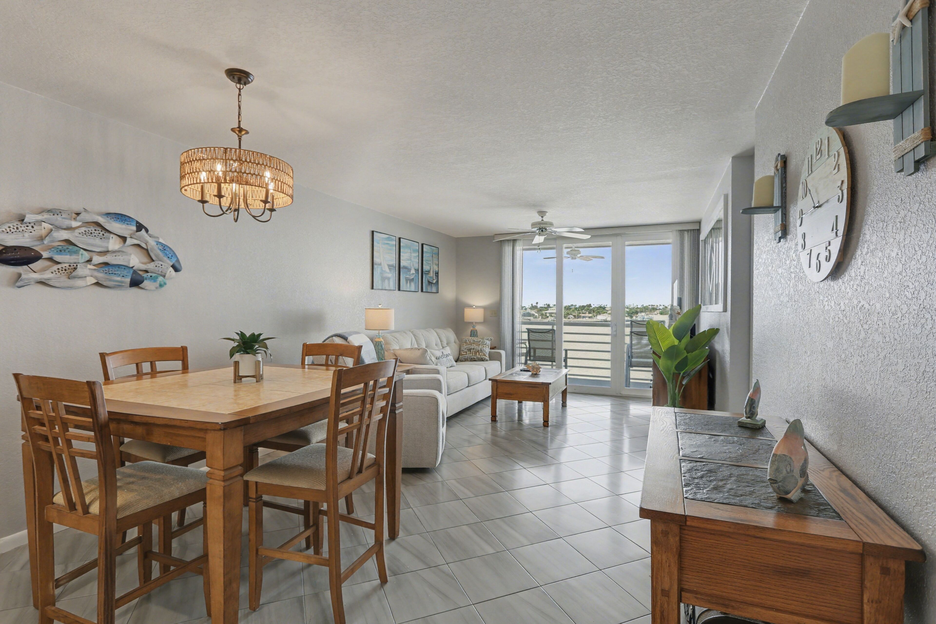 A spacious living area with a dining table, chairs, a sofa, and a ceiling fan.