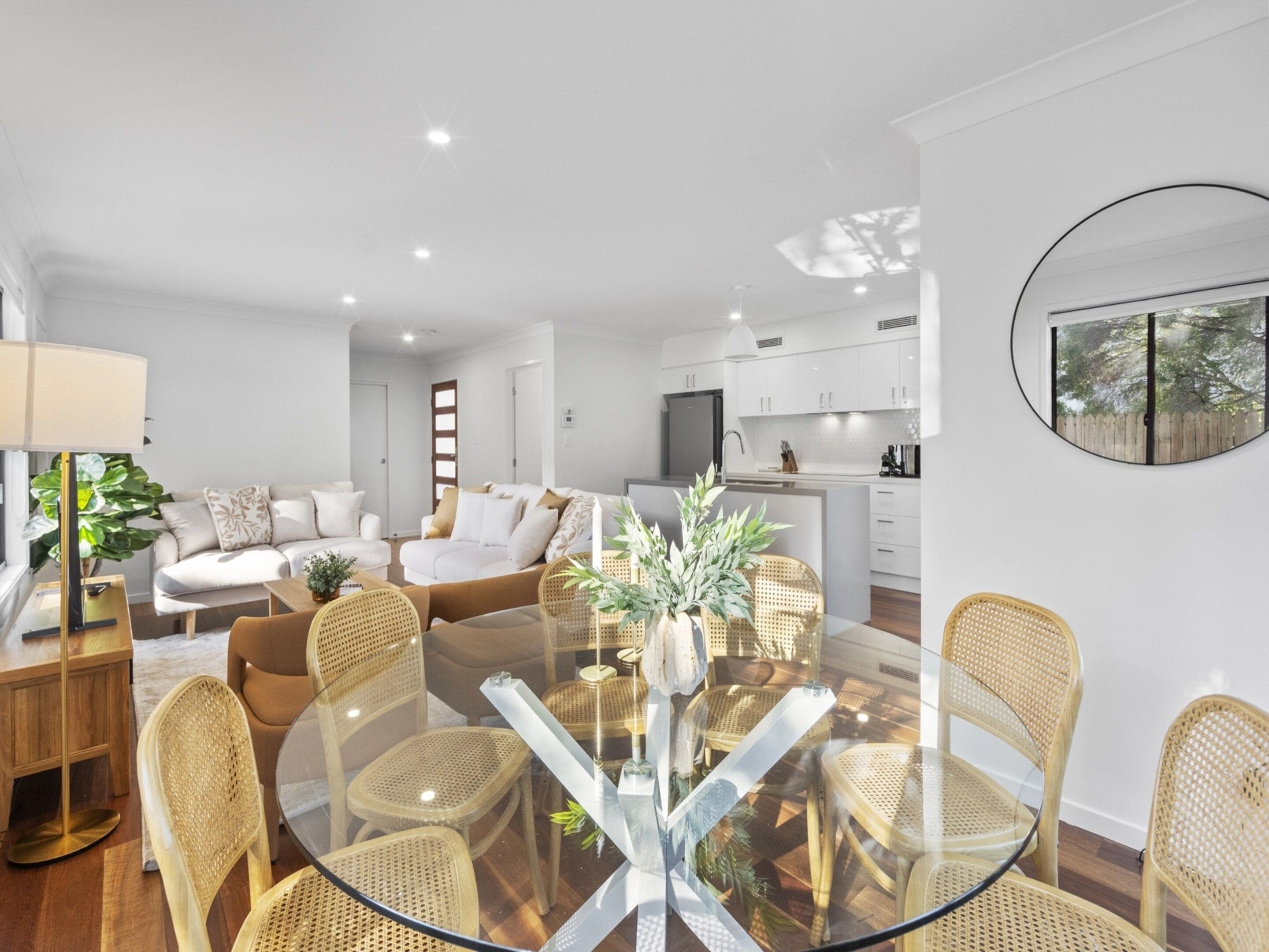 A modern living space with a dining area, sofa set, and kitchen.