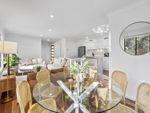 A modern living space with a dining area, sofa set, and kitchen. - Family Retreat With Garage and Outdoor BBQ (Brisbane)