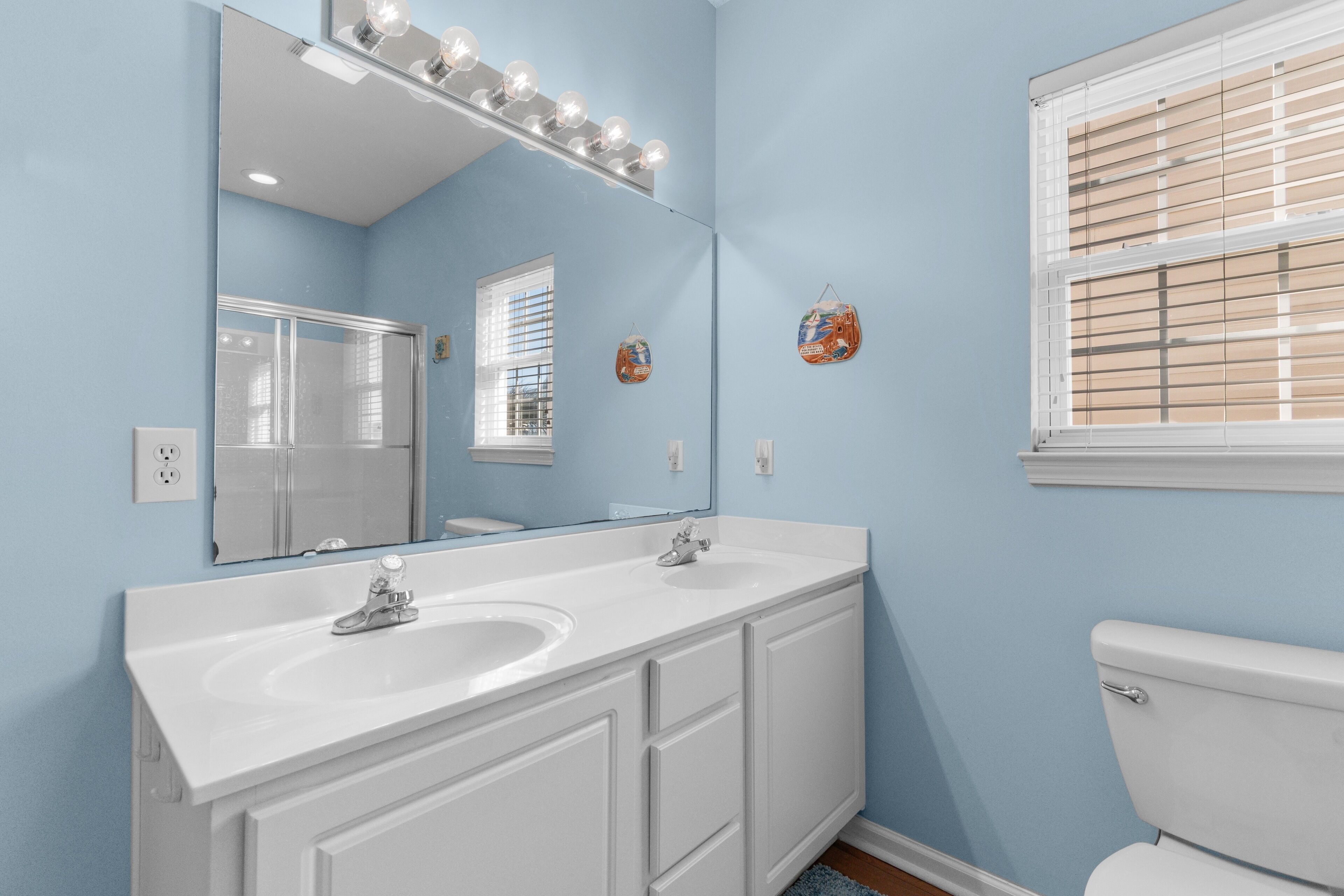 A bathroom with two sinks, a large mirror, and a toilet.