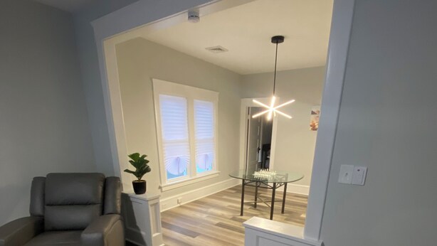 Un salon moderne avec un canapé en cuir gris, une table basse en verre et un plancher en bois.