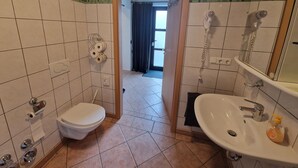 A bathroom with a toilet, sink, and shower. There is a towel rack and a toilet paper holder. - Apartment centrally located to the spa clinic incl. parking lot (Bad Oeynhausen)