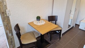 A small dining area with a wooden table and two chairs, a small potted plant, and a white fluffy placemat. - Apartment centrally located to the spa clinic incl. parking lot (Bad Oeynhausen)