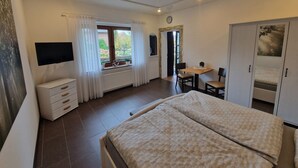 A bedroom with a bed, a TV, a desk with chairs, and a wardrobe. - Apartment centrally located to the spa clinic incl. parking lot (Bad Oeynhausen)