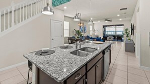A modern kitchen with granite countertops, a central island, and pendant lighting. - New 14 Guest Luxury Style Pool Villa-Prime Disney. (Davenport)