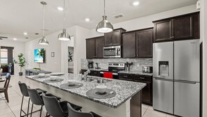 A modern kitchen with granite countertops, stainless steel appliances, and dark wooden cabinets. - New 14 Guest Luxury Style Pool Villa-Prime Disney. (Davenport)