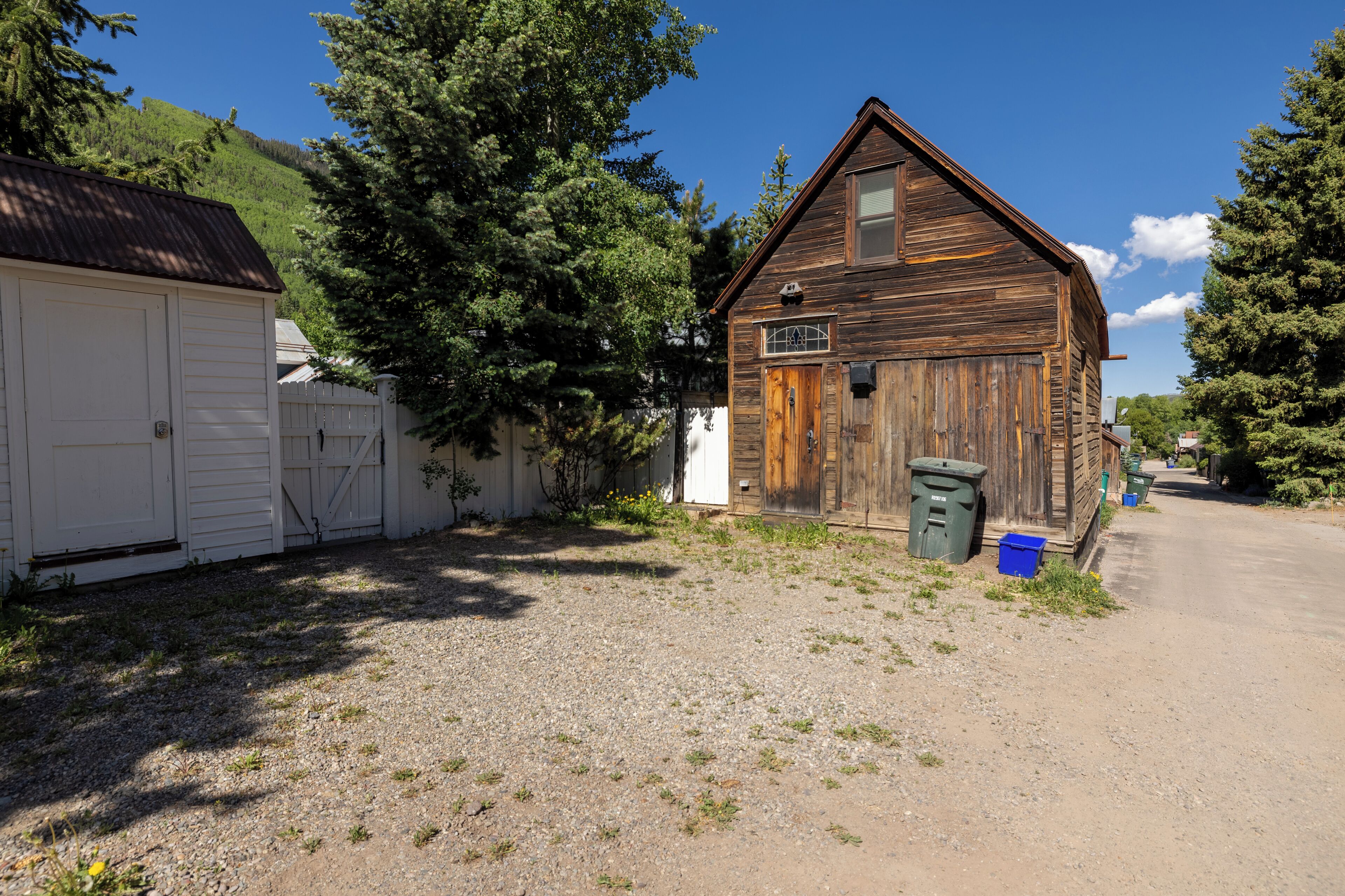 A rustic wooden building with a gravel driveway and a white garage.