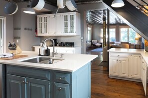 A modern kitchen with white cabinets, a central island with a sink, and a dining area with a view. - Your Luxury Private Telluride Getaway – Steps from Main Street & the Gondola (Telluride)