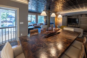 Eine moderne Küche mit einem großen Holztisch, Pendelleuchten und einer Steinwand.