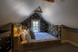 A loft bedroom with a sloped ceiling, a bed with white bedding, a nightstand with a lamp, and a window. - Your Luxury Private Telluride Getaway – Steps from Main Street & the Gondola (Telluride)