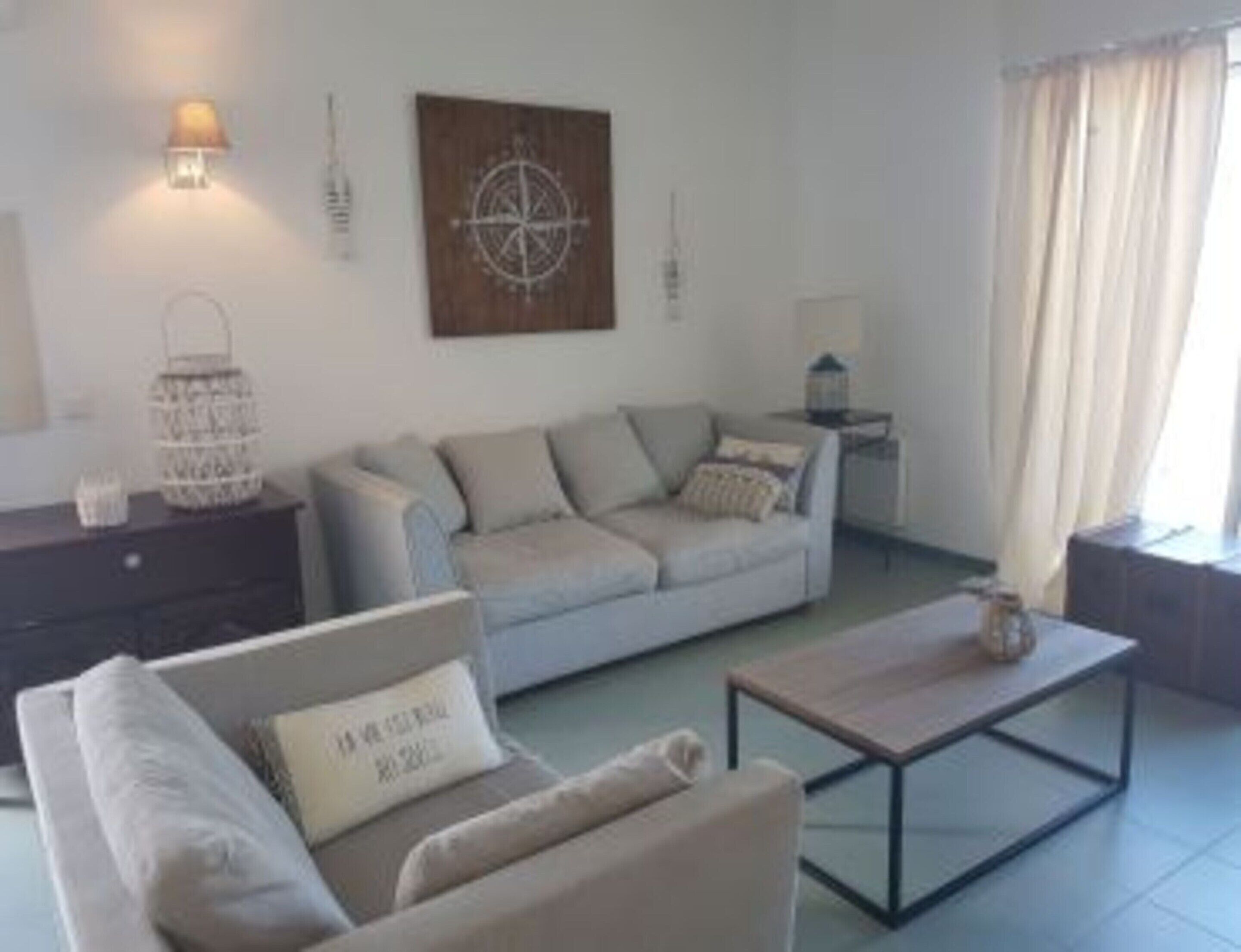 A living room with a sofa, a coffee table, a side table, and a wall-mounted lamp.