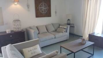 A living room with a sofa, a coffee table, a side table, and a wall-mounted lamp.