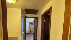 Un corridoio stretto con pavimento in legno e pareti bianche.