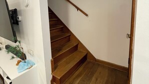 Una scala di legno con gradini che conduce a un pianerottolo, una parete bianca e un telaio di porta.