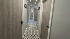 Un couloir avec des portes en bois, un sol à motifs et un luminaire au plafond.