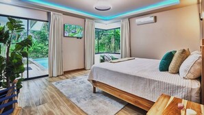 Ein Schlafzimmer mit einem Bett, Holzboden, einem großen Fenster und einer Deckenleuchte.