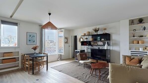 Uma sala de estar moderna com área de refeições, televisão e estante de livros.