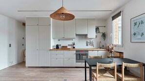 Uma cozinha moderna com armários brancos, uma mesa de jantar com cadeiras de vime e um pendente.