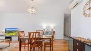 Een eethoek met een houten tafel en stoelen, een televisie waarop een landschap te zien is, en een wereldbol op de tafel.
