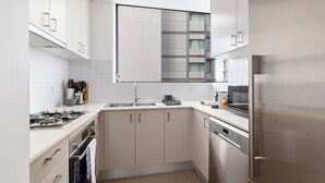 Een moderne keuken met witte kasten, roestvrijstalen apparatuur en een groot raam boven de gootsteen.