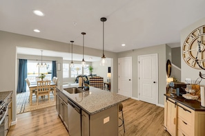 A modern kitchen with granite countertops, a central island, pendant lighting, and a view into the dining area. - Luxury 3‑BR townhome • Penn State • Sleeps 11 • EV Level 2 • State College (State College)