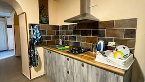 A kitchen with a central island, a stove, a sink, and a microwave. There is a towel rack and a dish rack on the island. - Wine Vanult Apartment Tbilisi (T'bilisi)