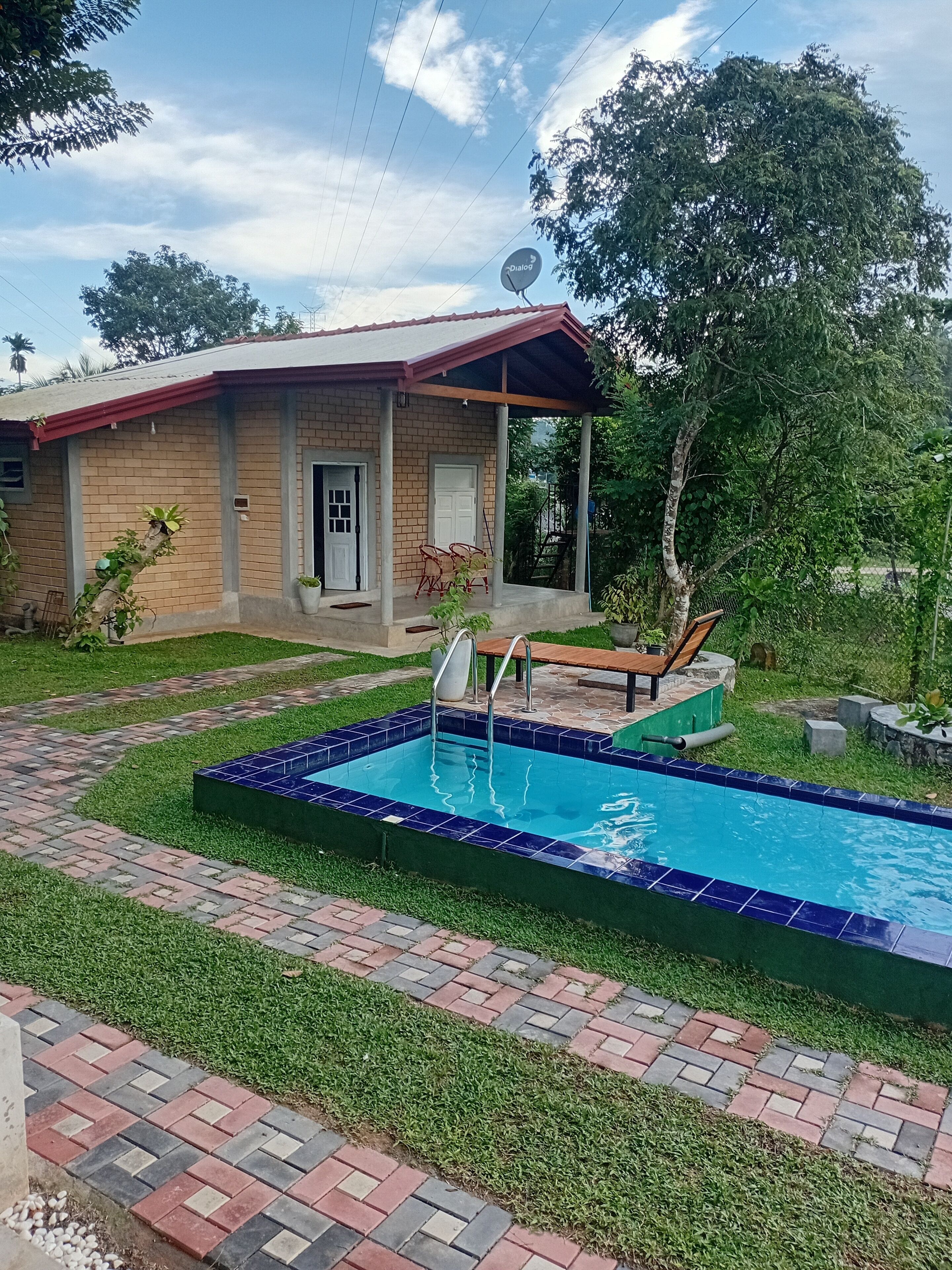 A house with a swimming pool, a covered porch, and a brick pathway.