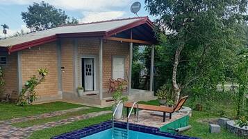 A house with a swimming pool, a covered porch, and a brick pathway.