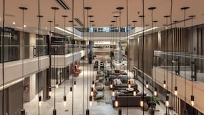 Ein geräumiges Atrium mit hängenden Pendelleuchten, Sitzbereichen und einer zentralen Treppe.