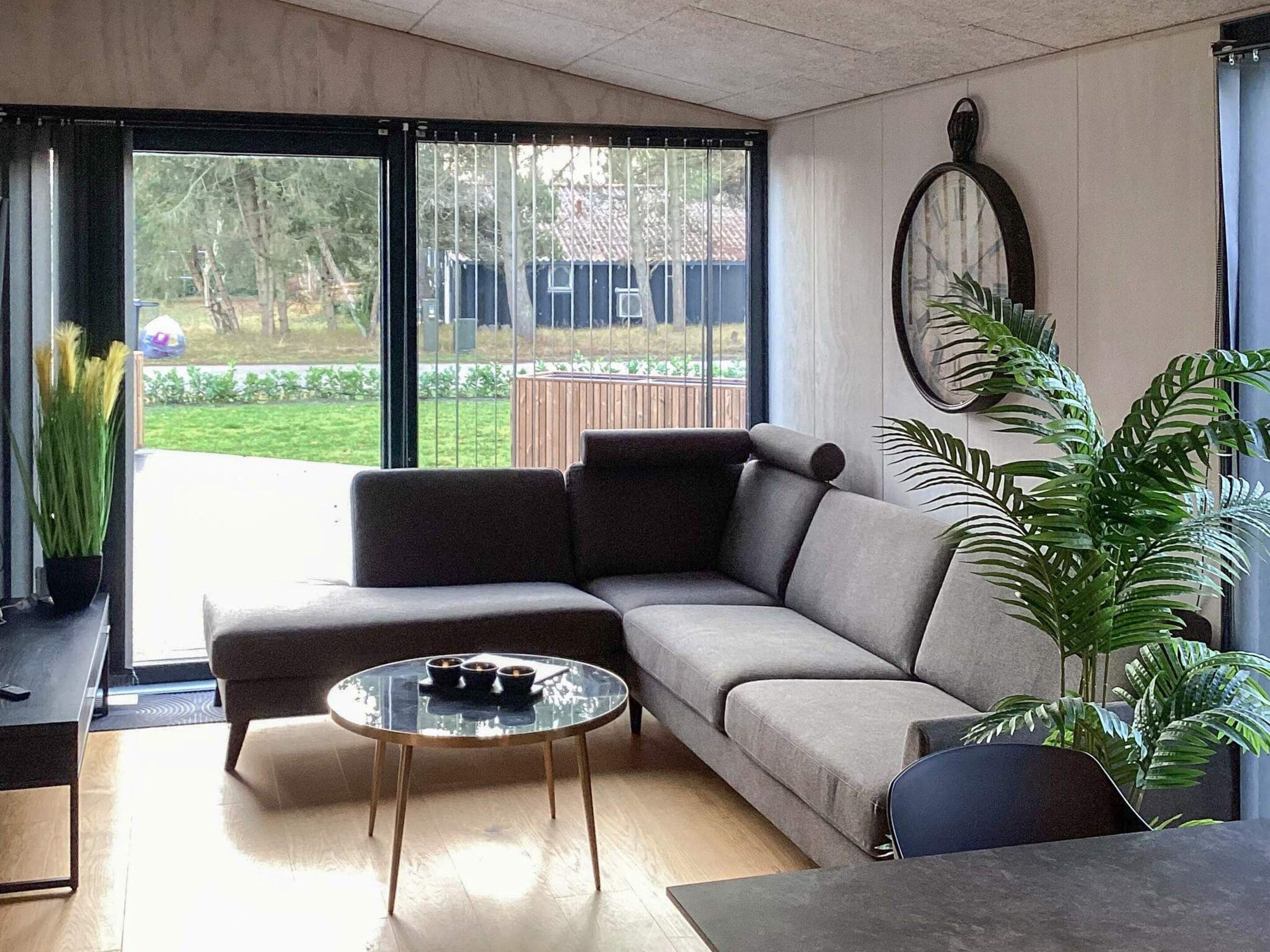 A modern living room with a sectional sofa, a glass coffee table, and a potted plant.
