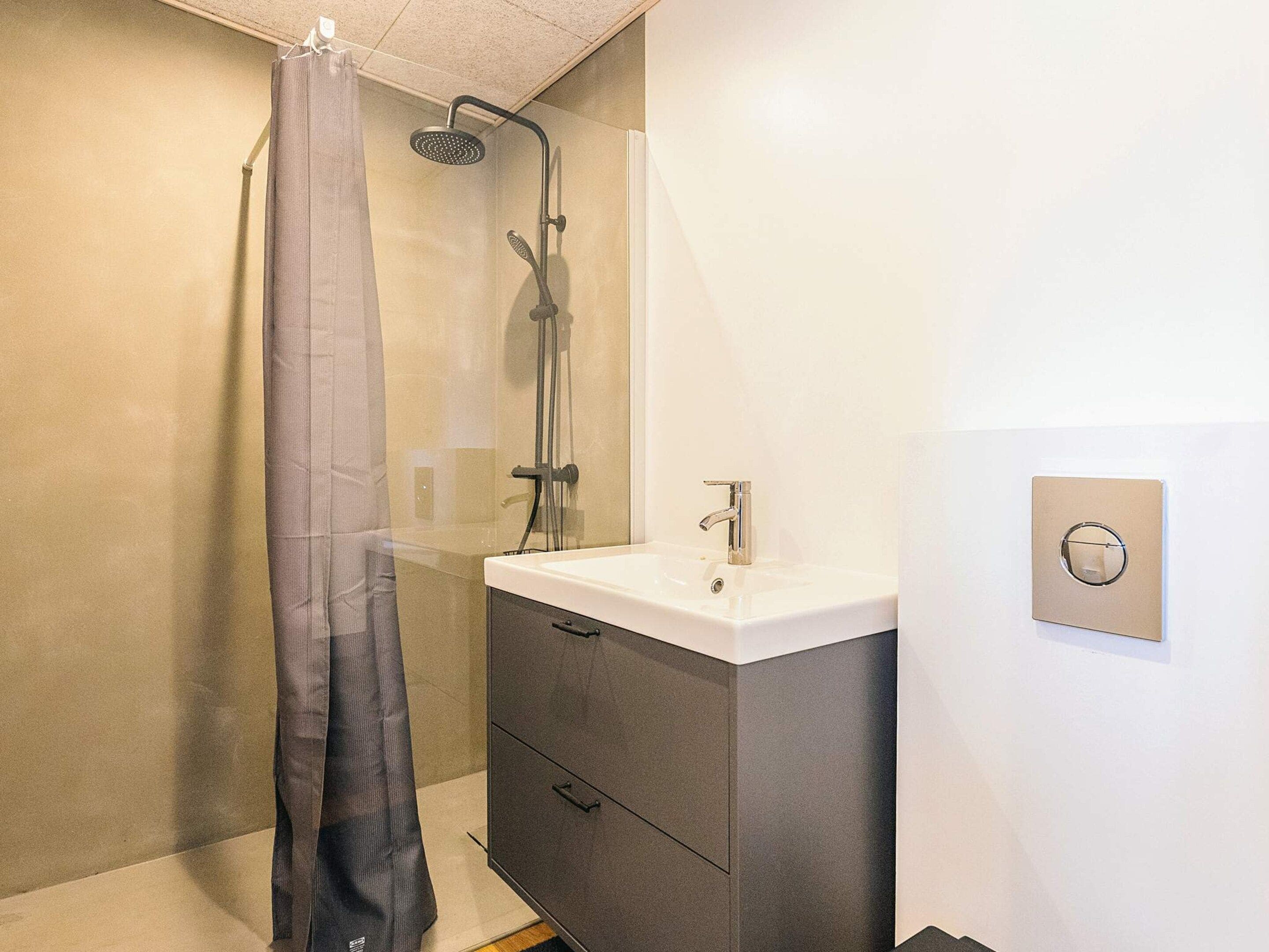A bathroom with a shower, a sink, and a cabinet.