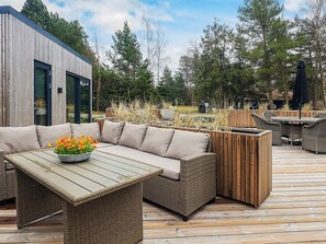 A wooden deck with a sofa, table, and outdoor furniture. - 5 Star Holiday Home in Vaeggerlose (Vaeggerlose)