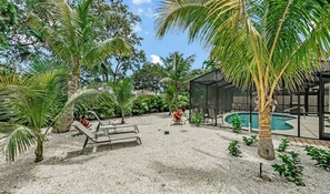 A pool area with lounge chairs, palm trees, and a covered seating area. - 2/2 pool home close to beach! (Bradenton)