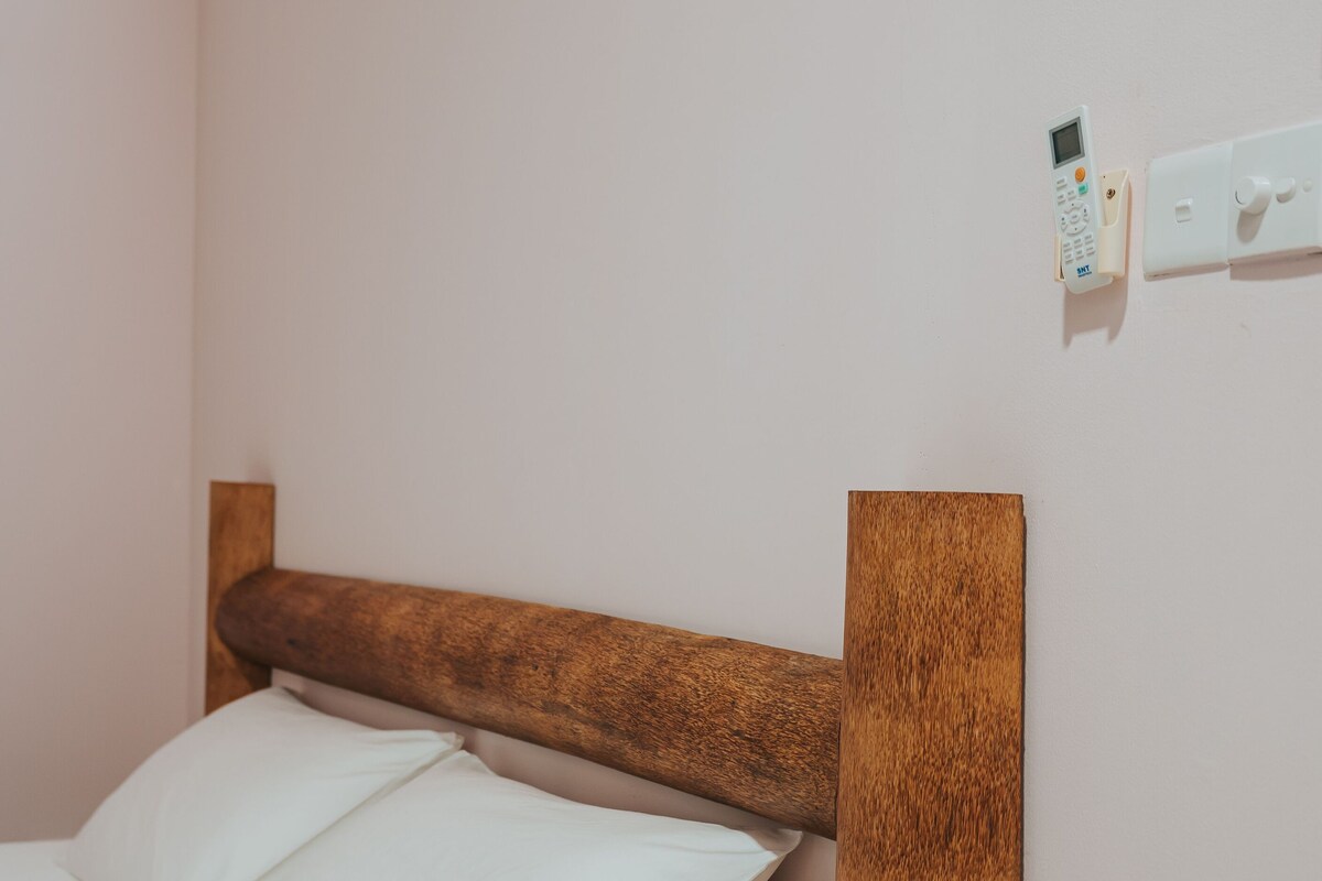 A bed with a wooden headboard and a small wooden nightstand beside it.