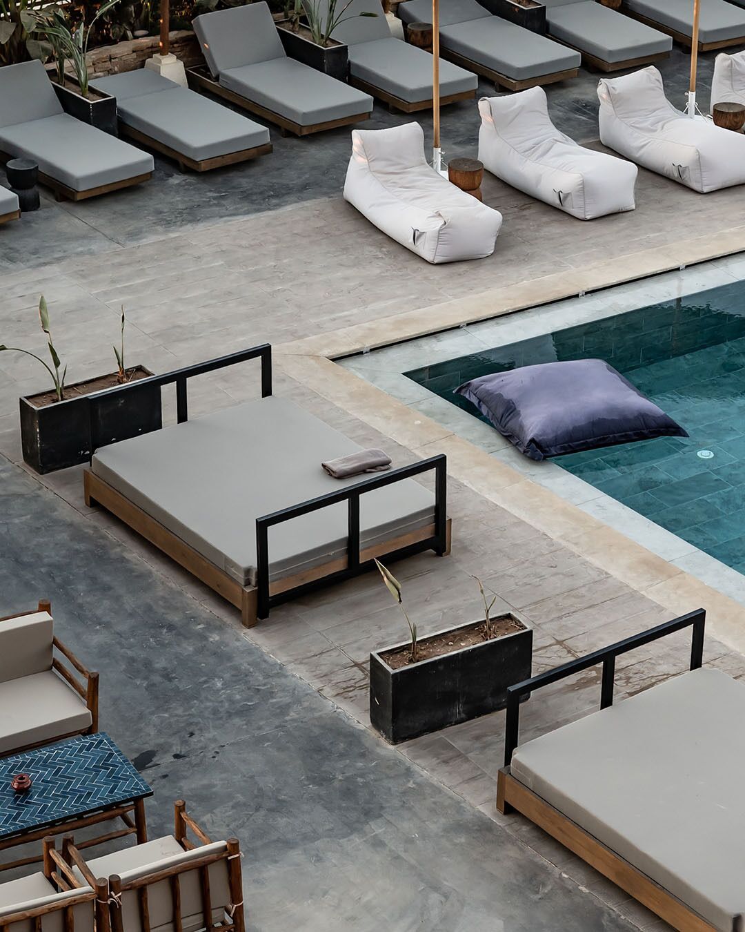 A rooftop pool area with multiple lounge chairs and a small table with chairs.