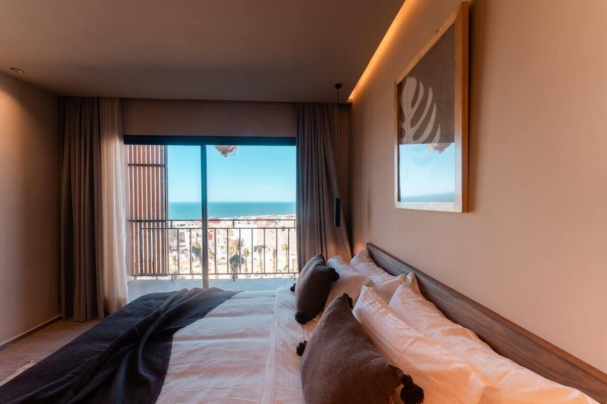 Ein Hotelzimmer mit Bett, Meerblick und einem Balkon.