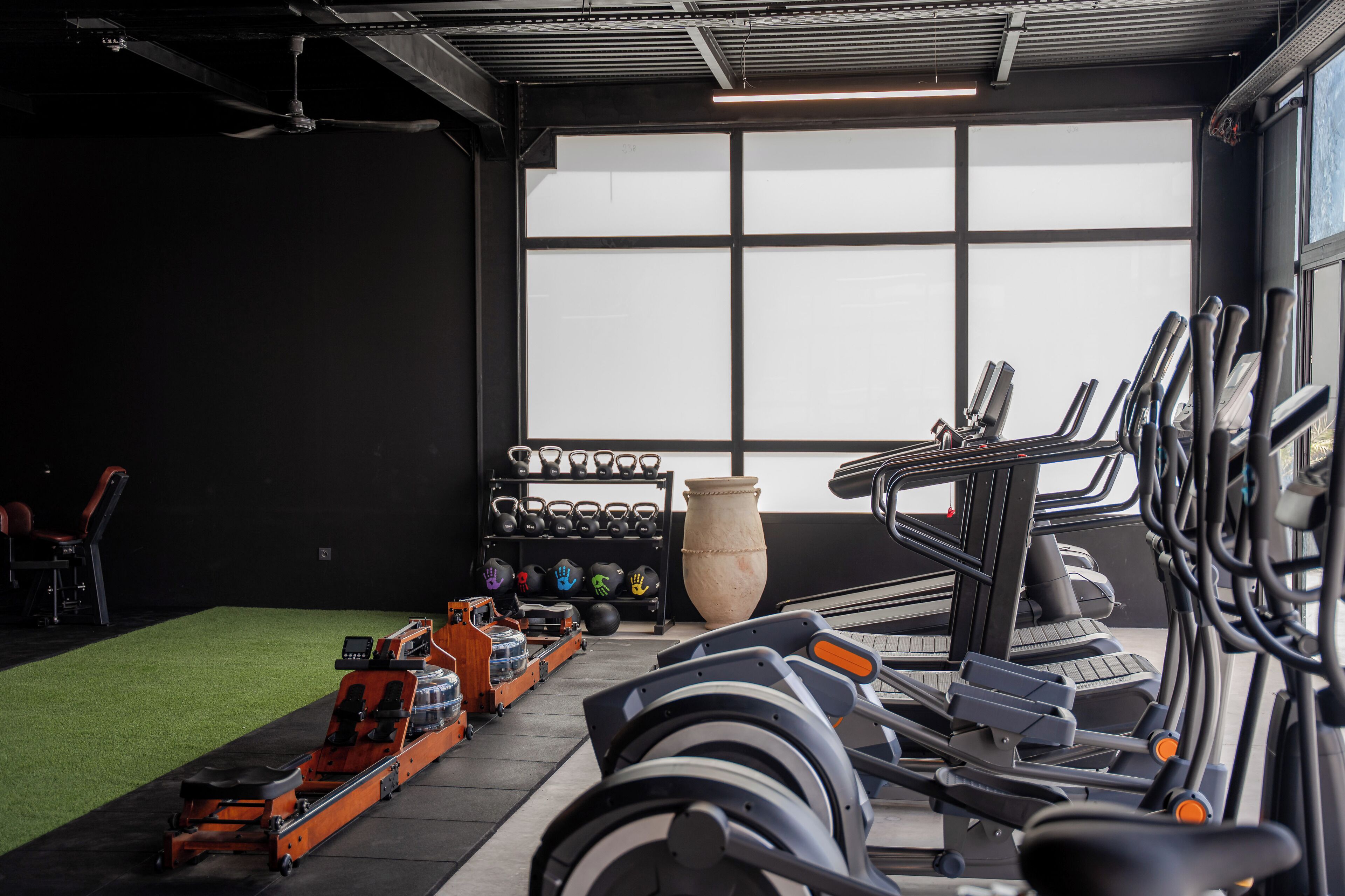 A gym with treadmills, weights, and a large vase.