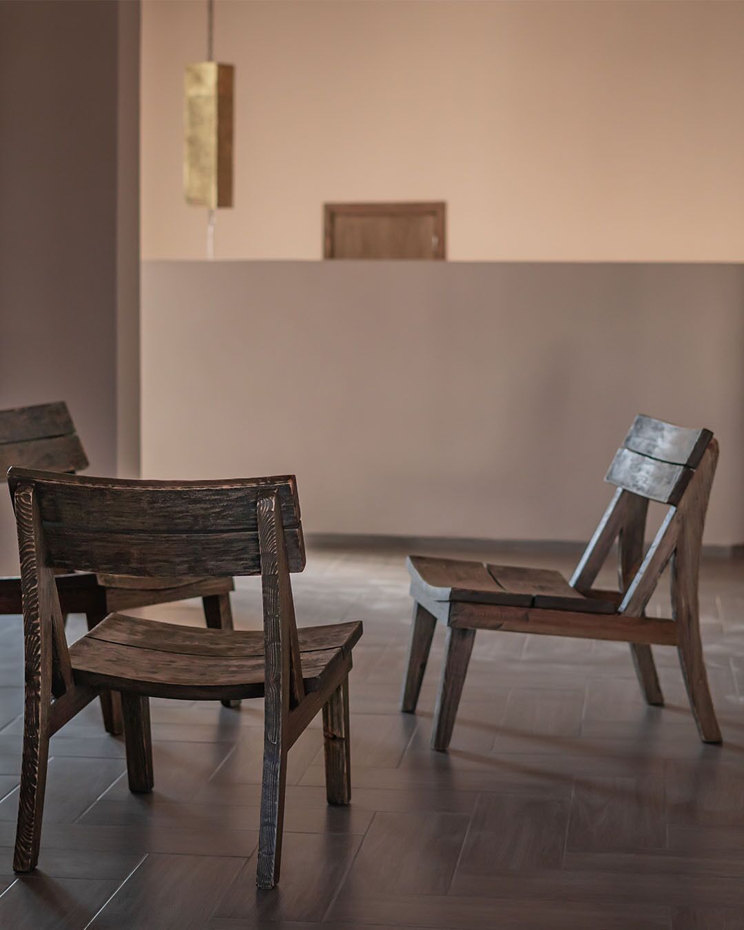 Two wooden chairs in a room with a tiled floor and a plain wall.