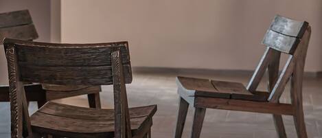 Two wooden chairs in a room with a tiled floor and a plain wall.
