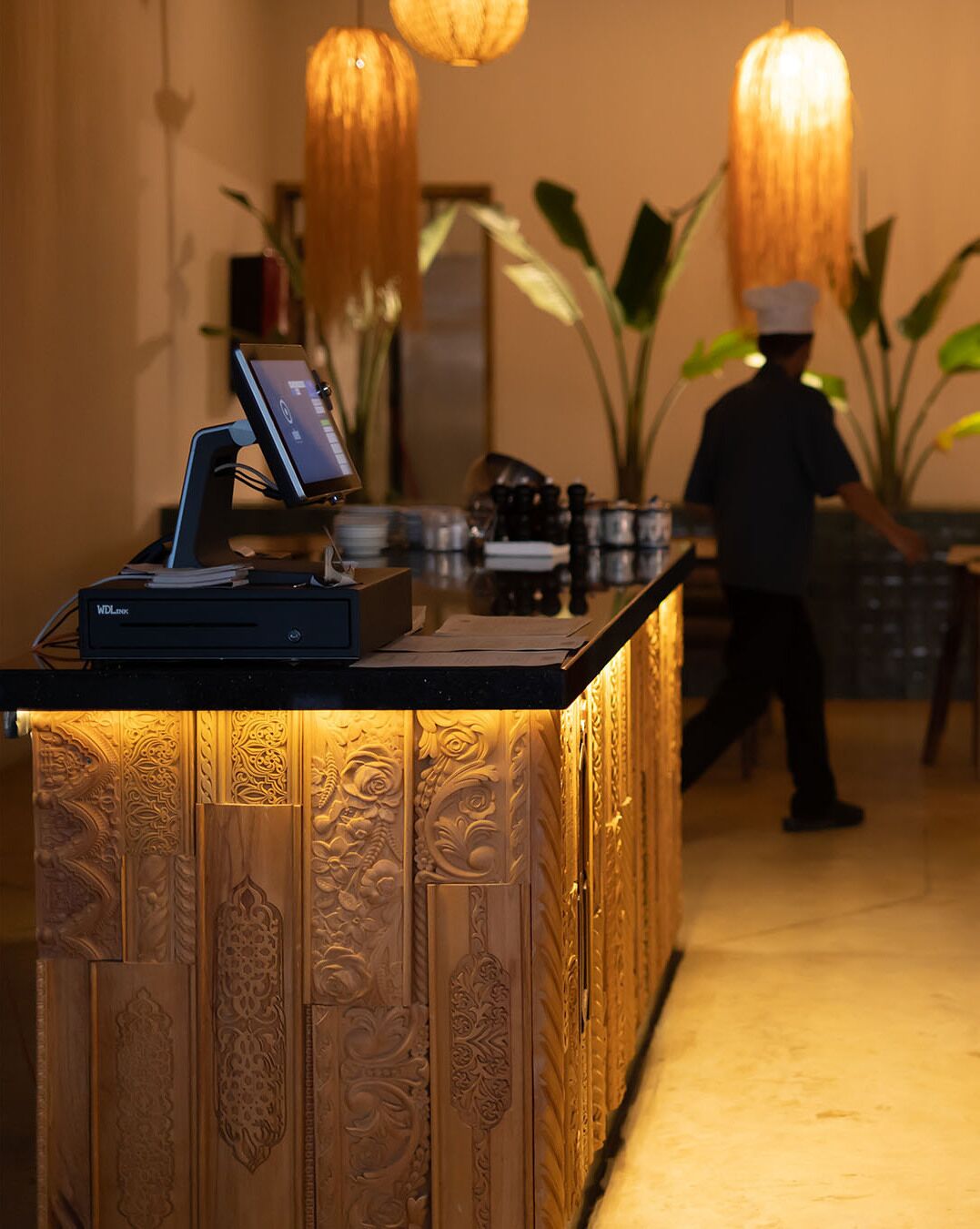 A reception desk with a digital display, a cash register, and a plant.