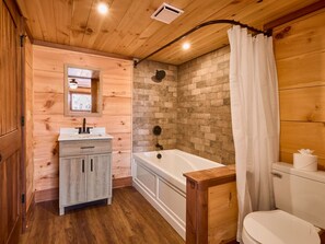 A wooden cabin bathroom with a wooden vanity, a bathtub, and a toilet.
