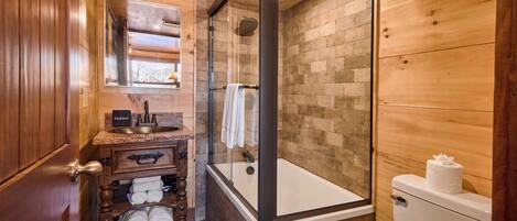 Une salle de bain en bois avec une douche à parois de verre, un lavabo avec un miroir et des toilettes.