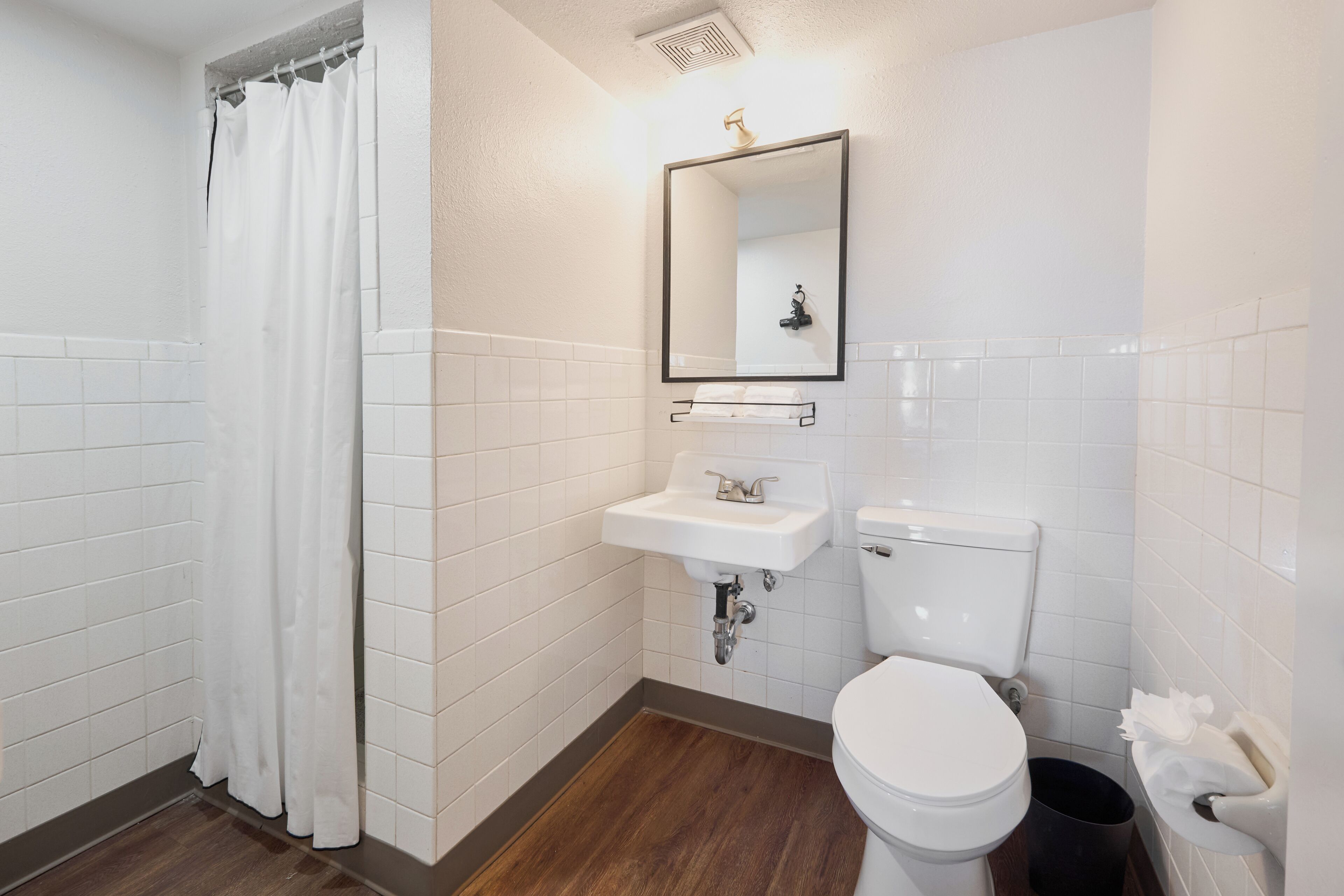 Un baño con lavamanos blanco, inodoro y cortina de ducha.