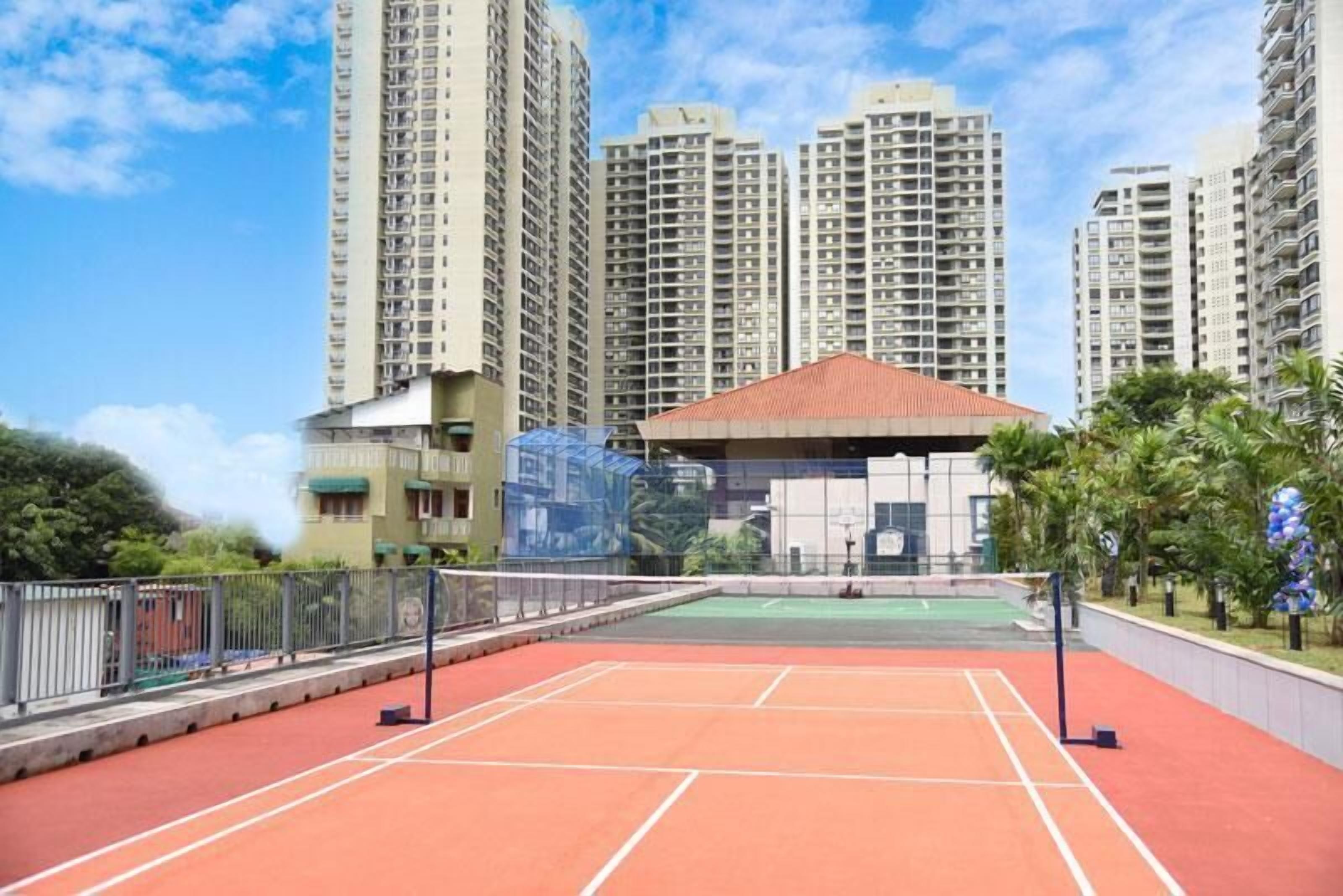 Una cancha de tenis rodeada de edificios altos y un pequeño pabellón.