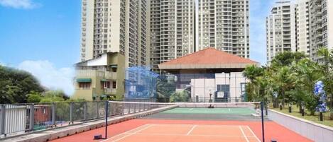 Una cancha de tenis rodeada de edificios altos y un pequeño pabellón.