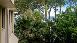 A building with a balcony overlooking a lush garden with various trees and plants. - Relaxing Getaway Steps Beach With Pool (Hervey Bay)