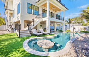 Une maison moderne à deux étages dotée d’une piscine, d’un espace salon extérieur et d’un patio couvert.